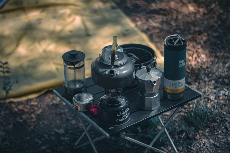 A cozy camping setup featuring coffee-making equipment and a tent outdoors. (Photo by Yaka Bagus on Pexels)
