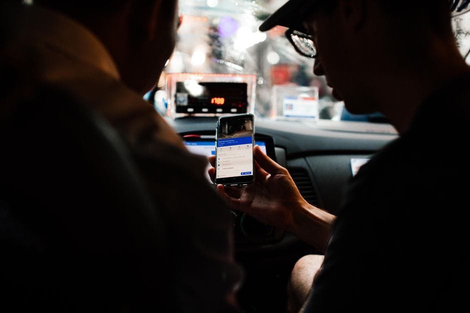 Two people using a smartphone for directions in a car at night. (Photo by Rachel Claire on Pexels)