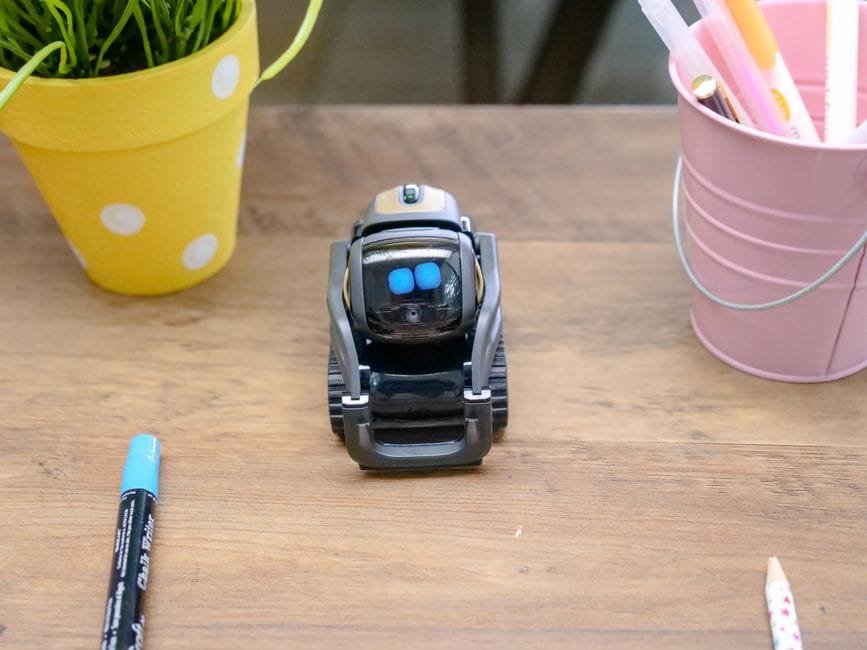 A small modern robot placed on a wooden desk surrounded by office supplies, showcases innovative technology. (Photo by Kindel Media on Pexels)