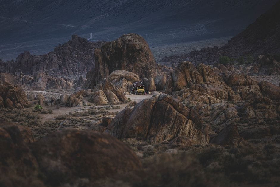 A yellow SUV set up for camping amidst rocky formations, showcasing rugged outdoor adventure. (Photo by Stephen Leonardi on Pexels)