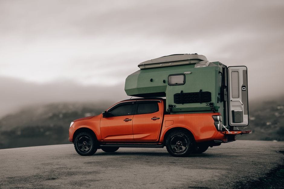 A vibrant orange pickup truck with a green camper stands on a mountain road in foggy Ordu, Türkiye. (Photo by M.Emin  BİLİR on Pexels)