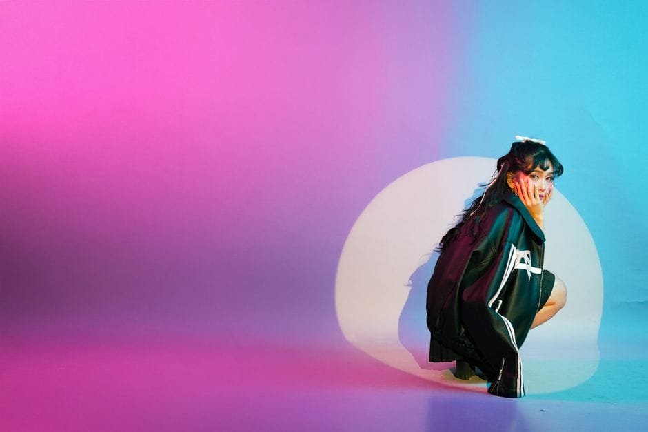 Vibrant studio portrait featuring a young woman surrounded by colorful lighting effects. (Photo by Kenneth Surillo on Pexels)