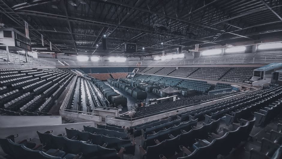 An empty stadium interior showcasing rows of seats and dramatic lighting. (Photo by Nestor Almonia on Pexels)