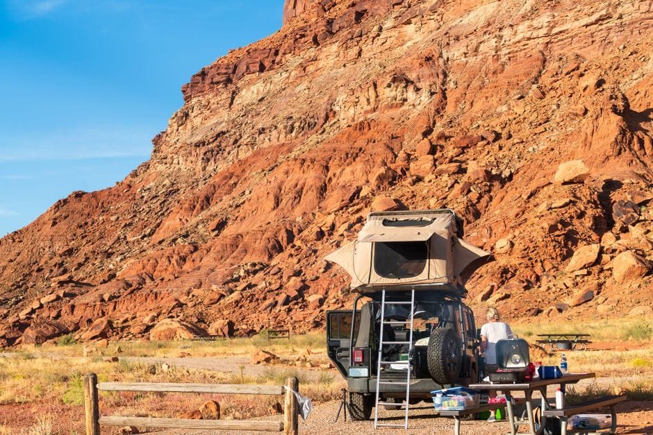 Explore the rugged beauty of Utah's desert with a campsite set against stunning red rock cliffs. (Photo by Frank Schrader on Pexels)