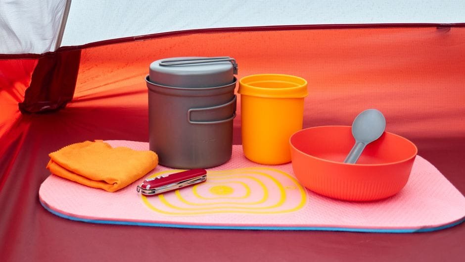 Colorful camping cookware and utensils arranged neatly inside a tent. (Photo by Mykhailo Petrushchak on Pexels)