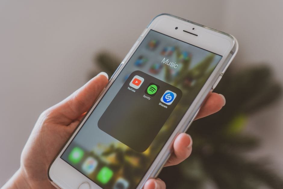 Hand holding a smartphone displaying popular music apps like Spotify and Shazam in a close-up shot. (Photo by Castorly Stock on Pexels)