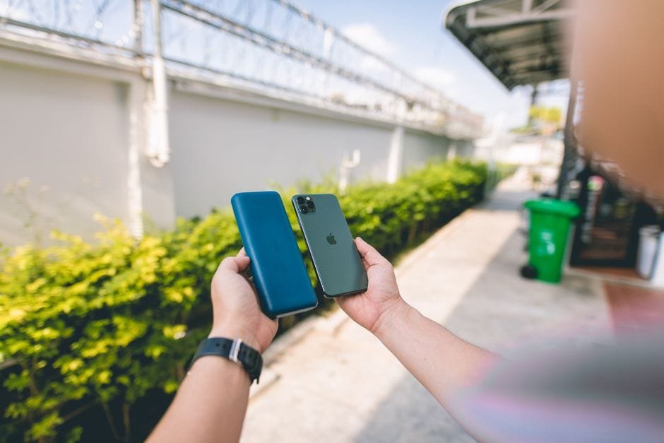 Close-up of a smartphone and power bank held in hands in an outdoor setting. (Photo by I'm Zion on Pexels)
