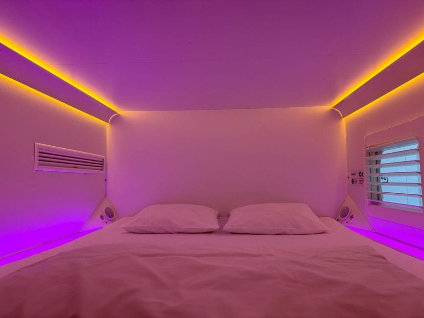 Cozy capsule hotel room with vibrant ambient lighting and minimalistic design. (Photo by Rufina Rusakova on Pexels)