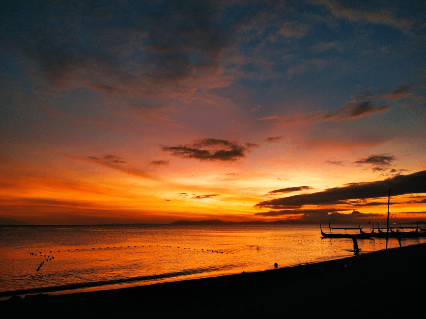 A breathtaking sunset over the beach with silhouettes of boats in Calabarzon, Philippines. (Photo by Loren Pacampara on Pexels)