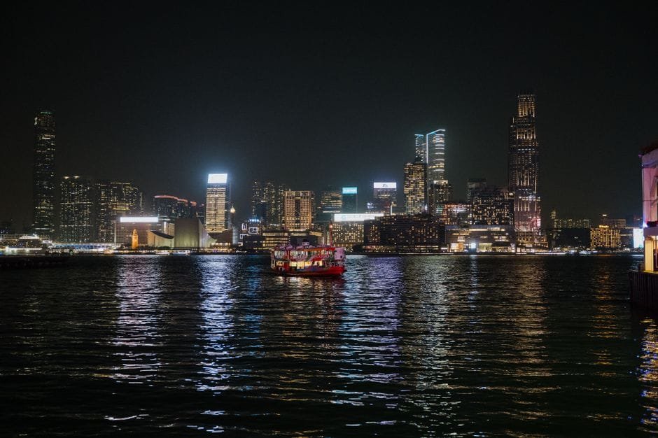Captivating view of Hong Kong skyline illuminated at night with ferries on Victoria Harbour. (Photo by Arnold Nagy on Pexels)