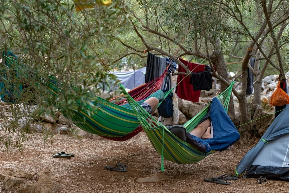 Two campers relaxing in hammocks amidst trees at Lastovo campsite, Croatia. (Photo by Filipa Beroš on Pexels)