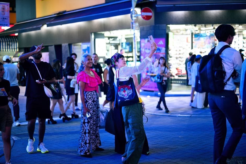People enjoying a lively night scene in Tokyo, capturing moments and exploring the city. (Photo by Federico Abis on Pexels)