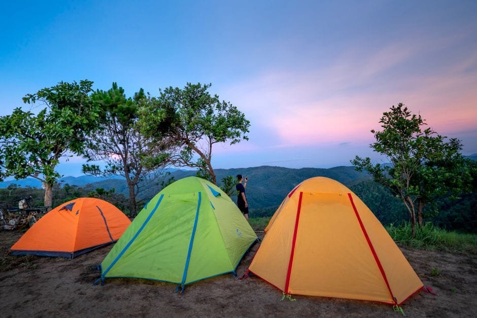 Colorful tents located at camp in mountainous valley near green trees against picturesque sunset sky (Photo by Quang Nguyen Vinh on Pexels)