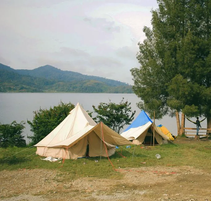 Peaceful lakefront camping scene with tents and mountains, ideal for nature and adventure seekers. (Photo by Padli Pradana on Pexels)