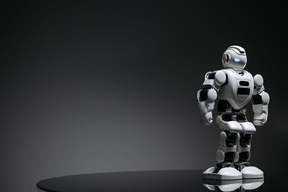 Compact humanoid robot toy standing on a reflective surface, exuding a futuristic vibe. (Photo by Pavel Danilyuk on Pexels)