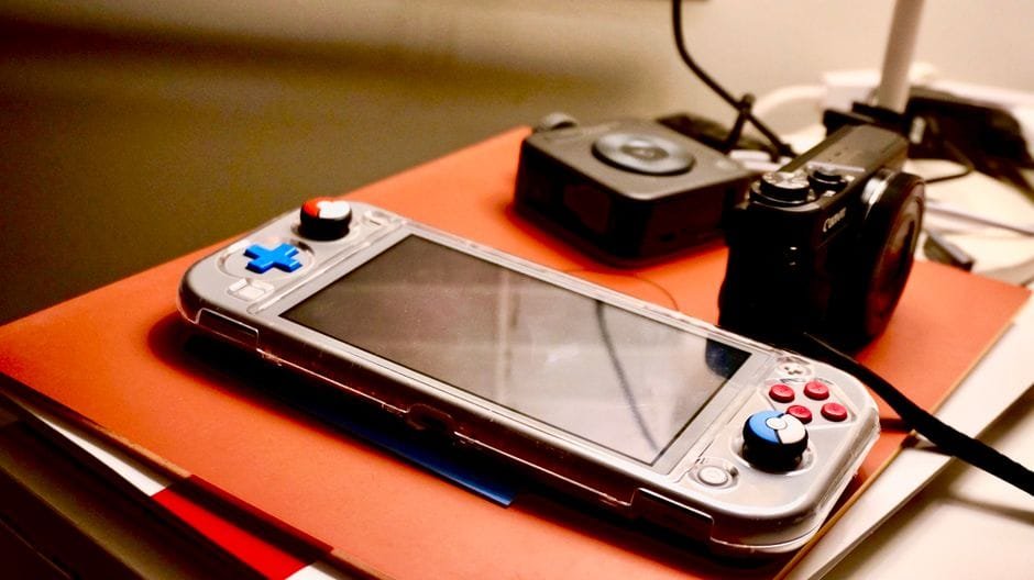 A portable gaming console beside a digital camera showcases modern entertainment and technology setup. (Photo by S.Mark. Gor on Pexels)