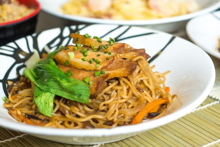 Close-up of a flavorful Asian noodle dish with pork, garnished with vegetables and herbs. (Photo by Marvin  Sacdalan on Pexels)