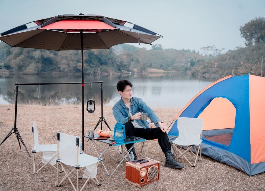 A man enjoying a peaceful camping vacation by a lake with tent and camping gear. (Photo by pham manh on Pexels)