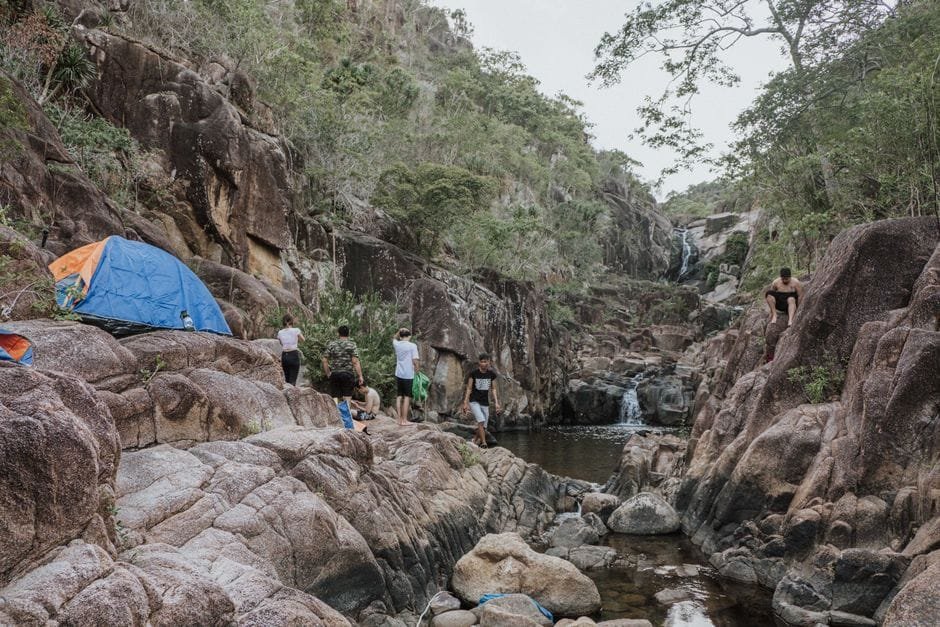 Explore a serene rocky canyon with a tent near a waterfall, perfect for camping adventures. (Photo by Windd on Pexels)