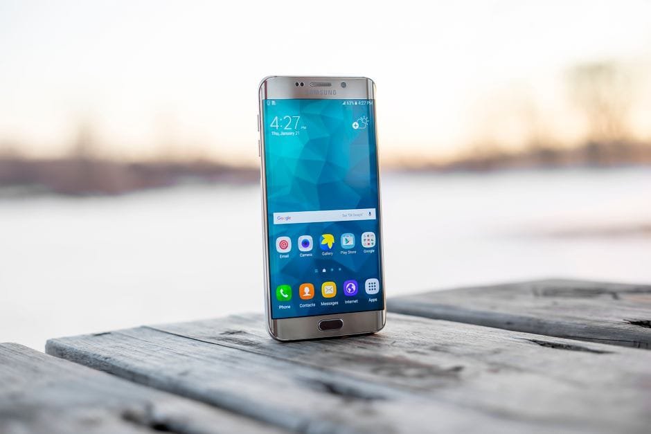 Samsung smartphone placed on a wooden surface outdoors during sunset. (Photo by MOHI SYED on Pexels)