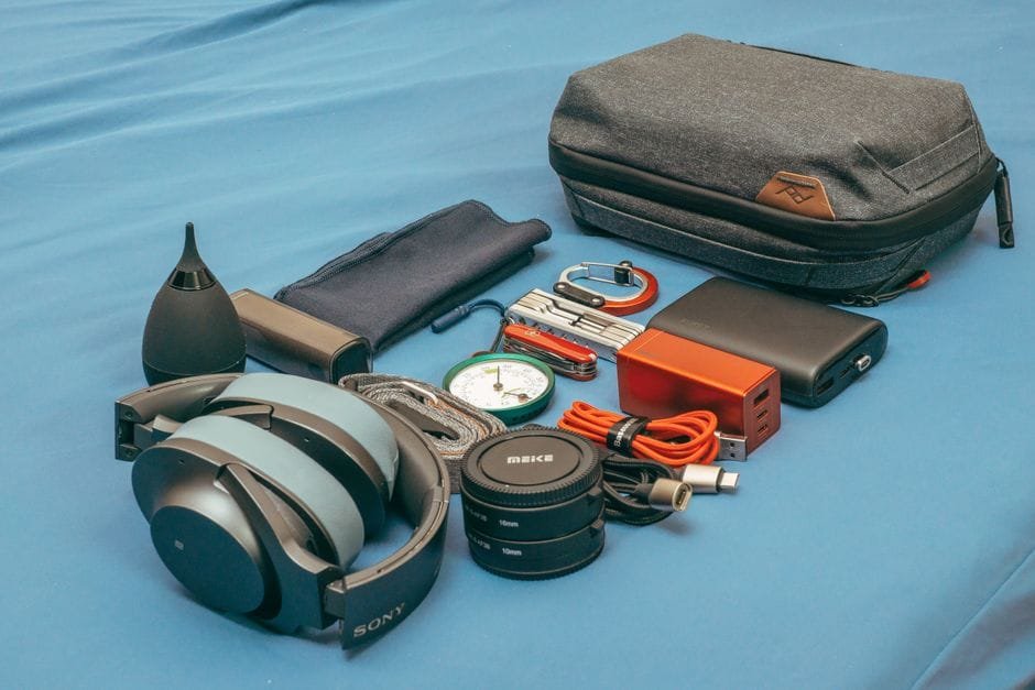 Flat lay of travel gear including headphones, a compass, power bank, and accessories. (Photo by FOX ^.ᆽ.^= ∫ on Pexels)