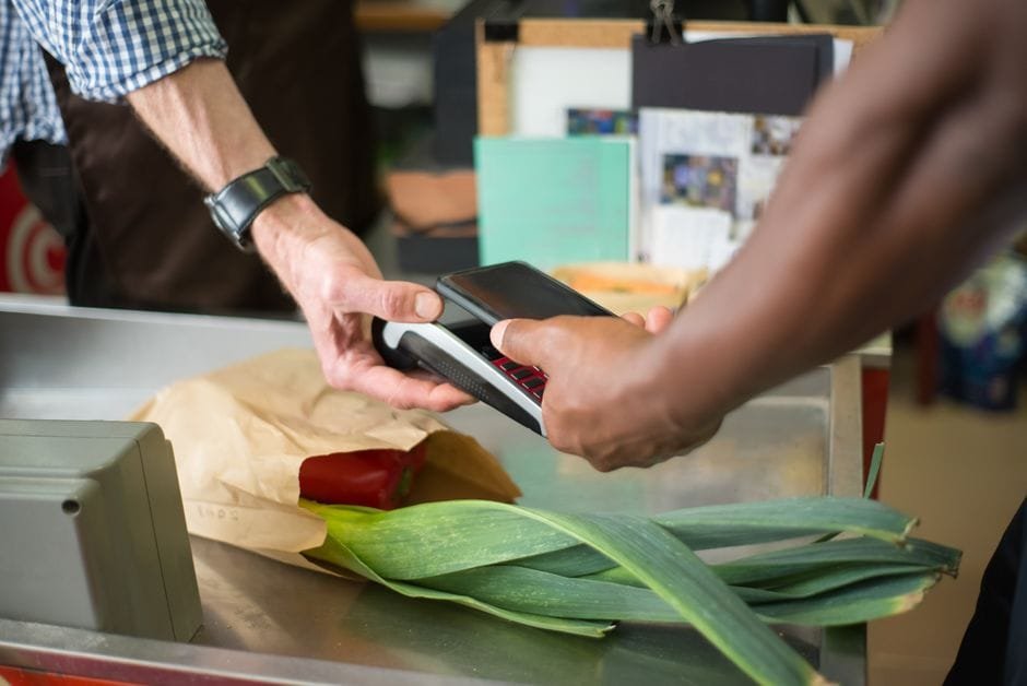 A customer making a contactless payment with a smartphone at a grocery store checkout counter. (Photo by Kampus Production on Pexels)