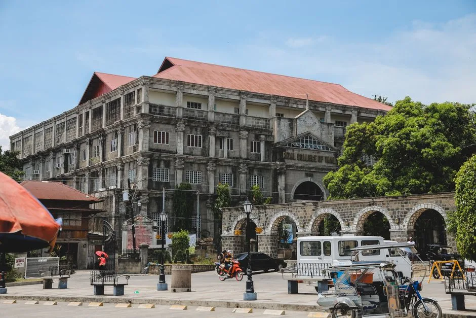 A classic college building surrounded by vibrant urban life and trees. (Photo by Denniz Futalan on Pexels)