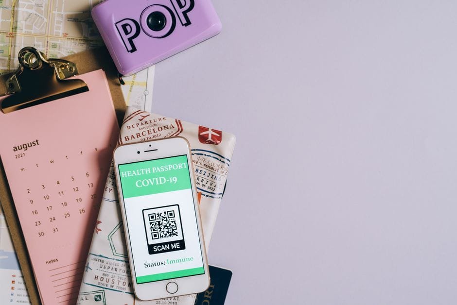 Flat lay image of a health passport with a COVID-19 QR code, calendar, and map. (Photo by Leeloo The First on Pexels)