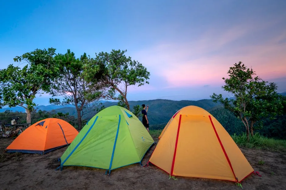 Colorful tents located at camp in mountainous valley near green trees against picturesque sunset sky (Photo by Quang Nguyen Vinh on Pexels)