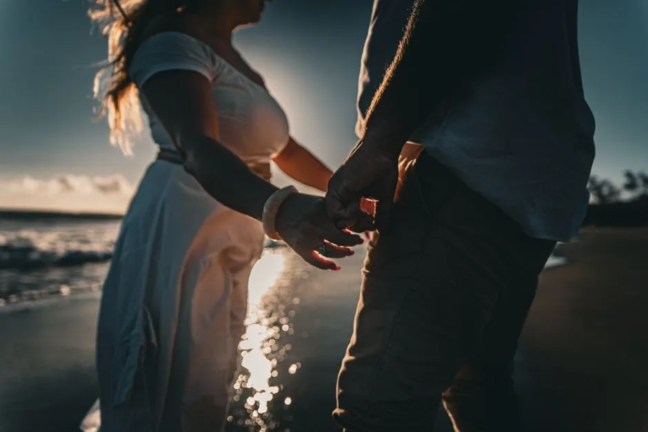 Silhouetted couple holding hands at sunset on Saint-Leu beach, La Réunion. (Photo by Nicolas Lesueur on Pexels)