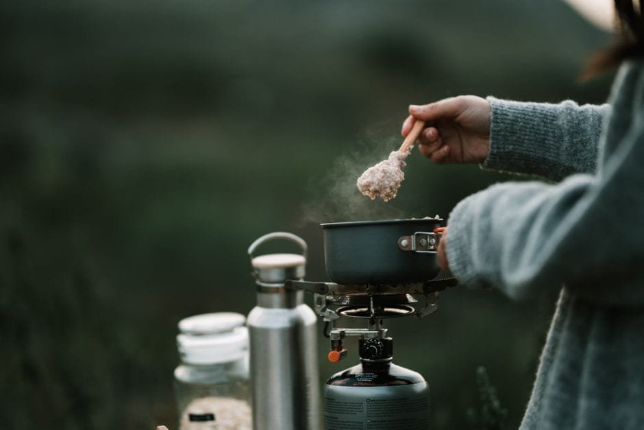 A person is cooking steaming oatmeal on a portable stove during a camping trip. (Photo by Taryn Elliott on Pexels)