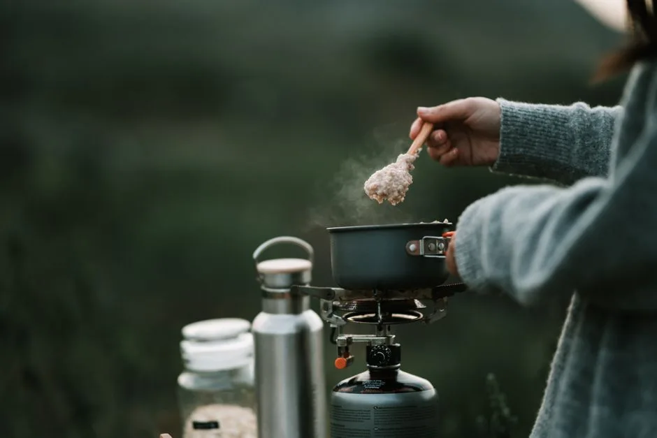 A person is cooking steaming oatmeal on a portable stove during a camping trip. (Photo by Taryn Elliott on Pexels)