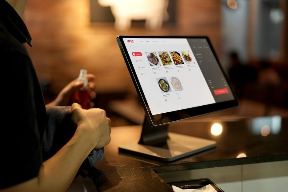A person using a touchscreen ordering system in a modern restaurant setting. (Photo by iMin Technology on Pexels)